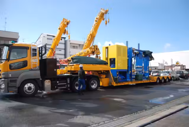大型設備を積載した低床トレーラーと荷役用クレーン