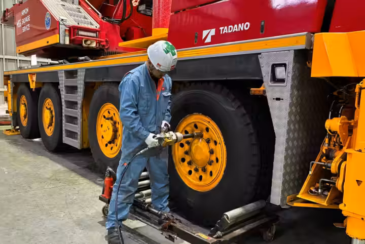 大型クレーン車の車輪周辺を整備する作業員
